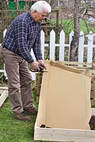Construction de parterres surélevés dans un petit jardin. Mettre une couche de carton pour garder les mauvaises herbes vers le bas.