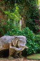 L'un d'une paire d'éléphants encadrant l'entrée de la Cour Sud avec Clématite 'Etoile Violette' escaladant la guérite derrière. Jardin du manoir de Cranborne, Dorset
