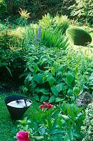 'Spinning Top 'de Lucy Strachan, une sculpture d'astroturf pour le jardin, sur la pelouse derrière Phlomis russeliana et un petit vase rempli d'eau