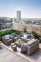 Coin salon extérieur avec des meubles de jardin en rotin sur un jardin terrasse sur le toit de Londres au printemps, avril