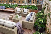 Coin salon extérieur sur une terrasse sur le toit de Londres avec table en verre avec un vase d'anémones blanches. Avril.