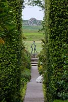 Vue vers le bas Les marches de Neptune à travers les haies de Quercus Ilex jusqu'à la sculpture - 'Tresco Children' de David Wynne. Jardins de l'abbaye de Tresco, Tresco, îles Scilly.