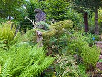 Une sculpture en bois d'un aigle par Simon O ' Rourke, entouré de fougères à Mount Pleasant Gardens, Kelsall, Cheshire photographié en juin