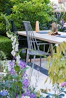 Le LG Smart Garden, vue d'un patio avec chaises et table en bois conçu par Nils Verweij entouré de fleurs printanières aux couleurs pâles. RHS Chelsea Flower Show 2016. Concepteur: Hay Young Hwang, sponsors: LG Electronics