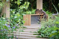 Un panneau en bois et un banc en chêne et un chemin en dalles de chêne dans The Garden of Potential. The RHS Chelsea Flower Show 2016 - Designer: Propagating Dan - Sponsor: GreenWood Forest Park - SILVER-GILT.