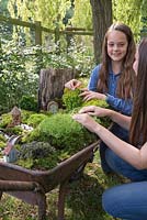 Jardin de brouette miniature. Deux jeunes filles construisant un jardin miniature à l'intérieur d'une brouette