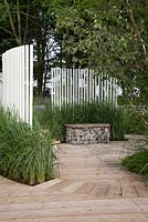 Graminées, clôture à lattes de bois blanc et assise en gabion. Jardin: 'Un jardin de prison pour la réhabilitation' au RHS Tatton Park Flower Show 2012