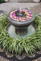 Fontaine d'eau remplie de fleurs en pierre grise dans la cour jardin avec mosaïque en pierre, Cordoue, Espagne
