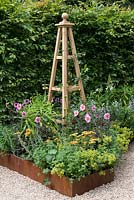 Un jardin inspiré des arts et de l'artisanat avec une haie de charme, un parterre de fleurs en acier corten surélevé et un obélisque fabriqué à la main. Une retraite d'été conçue par Laura Arison et Amanda Waring. RHS Hampton Court Flower Show 2016
