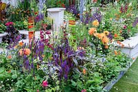 New Horizons City Garden. Panneaux en verre fondu coloré dans un parterre de fleurs orange, rouge et bleu. Designers: Beautiful Flowerbeds, Sponsors: Beautiful Flowerbeds Garden Design. RHS Hampton Court Palace Flower Show 2016