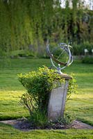 Un cadran solaire armillaire est placé au centre de la pelouse avec Rosa 'The Fairy'