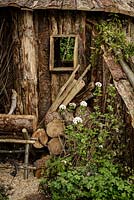 Cabane en bois rustique du bûcheron avec grumes empilées, cheval de scie et plantation de bois, y compris Viburnum - The Woodcutter's Garden - RHS Malvern Spring Show 2016. Concepteur: Mark Walker, parrain: Howards Motors