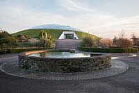 Un étang circulaire alimentant un ruisseau incurvé en face de la grande serre conçue par Norman Foster and Partners au National Botanic Garden of Wales en décembre.