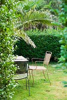 Table et chaises en métal à l'intérieur d'une des 'chambres privées' du jardin qui protègent des vents dominants