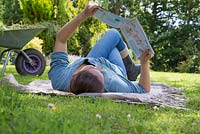 Jeune fille portant sur un tapis en lisant un magazine dans le jardin