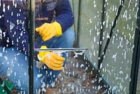 Nettoyage des vitres sales d'un petit patio à effet de serre