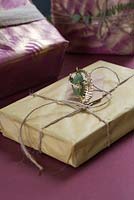 Un cadeau emballé avec une étiquette cadeau naturelle d'eucalyptus et de feuillage de fougère peint à la bombe d'or