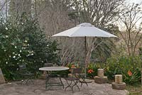 Table et chaises en bois et métal en plein air avec parasol blanc sur la terrasse avec Camellia et Clivia miniata - Septembre, l'hôtel Vineyard, Cape Town, Afrique du Sud