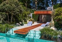 Jardin de luxe avec terrasse ensoleillée, cascade et piscine. Transats lilas sculptés contemporains et le toit planté de lavande