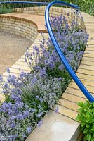 Rampes bleues incurvées au-dessus des bancs de briques avec Lavandula 'Hidcote '. The Abbeyfield Society: a Breath of Fresh Air, RHS Hampton Court Palace Flower Show 2016. Design: Rae Wilkinson