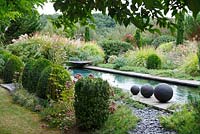 Trois boules de grès sont placées au bord de la piscine du Jardin Contemporain, Les Jardins de la Poterie Hillen