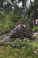 Fontaine décorative de pierres plates en gradins dans les jardins tropicaux avec maison de canard derrière - Lake Atitlan Hotel, Guatemala