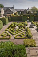 Une vue de la maison à travers le jardin de fantaisie avec son motif rose Tudor fabriqué à partir de la boîte - juin, Herterton House, Hartington, Northumberland, UK