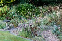 Little Ash Garden, Fenny Bridge, Devon. Bain d'oiseaux dans le jardin de gravier avec Verveine bonariense et sculptures en métal