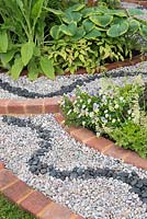 Détail de gravier avec parterres de fleurs bordés de briques - Spa Garden - Je suis les eaux et le vent, RHS Malvern Spring Festival 2017 - Conception: Annette Baines-Stiller