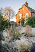 Le jardin de gravier devant la maison comprend de petits conifères traînants Larix decidua 'Puli', Ophiopogon planiscapus 'Nigrescens' et des herbes. 'Windy Ridge, Little Wenlock, Shropshire, Royaume-Uni