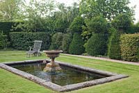 Étang et fontaine en pierre vieillie avec banc en bois. Jardin: Rustling End Cottage, Hertfordshire. Propriétaires: M. et Mme Wise
