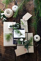 Beaucoup de cadeaux enveloppés de papier brun et blanc et attachés avec de la ficelle, avec des étiquettes-cadeaux et de la ficelle. Décoré de sapin, d'if et de feuillage argenté