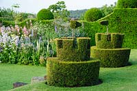 Des châteaux topiaires avec des drapeaux surplombent les plates-bandes herbacées. Felley Priory, Underwood, Notts, Royaume-Uni
