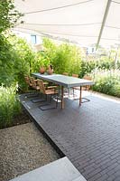 Petit jardin de ville avec terrasse contemporaine et voile solaire