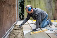 Niveler le ciment avec une truelle avant de poser un pavé en pierre sur le patio