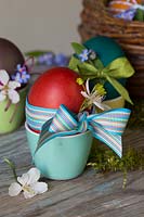 Oeufs de Pâques teints décorés avec ruban, fleurs délicates et ficelle