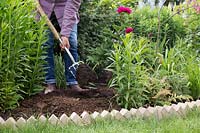 Ajouter du fumier dans le parterre de fleurs avec une fourchette pour améliorer le sol