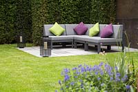 Canapé d'angle avec coussins colorés dans un jardin de banlieue contemporain