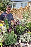 Antony Henn de Garden sur un rouleau de parterre nouvellement planté de plantes matures où les plantes sont placées selon le plan papier pour le parterre conçu