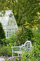 Endroit isolé avec banc de jardin sous un chêne anglais mature, obélisque comme support de roses et de clématites soutenu par une véranda. Création: Carol Bruce