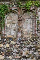 Partie de mur «médiéval» comprenant des «alcôves» pseudo-ecclésiastiques et des briques et silex décoratifs. L'usine de fuite est Cymbalaria muralis - Kenilworth Ivy.