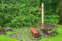 Patio dalle avec banc en bois rouge et table en dalle de pierre bordée de Thuja occidentalis - haie de cèdres dans une cour résidentielle à la fin du printemps, Québec, Canada.