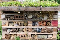 Un hôtel d'insectes construit à partir de chutes de bois, de briques restantes, de longueurs de bambou, de branches, de paille et de tuyaux.