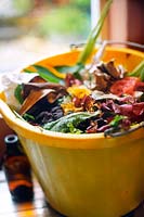 Déchets de cuisine collectés dans un seau pour être ajoutés au tas de compost