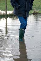 Homme portant des bottes Wellington debout dans un champ inondé, mars