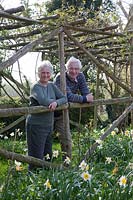 Propriétaires Jennifer et Edward en pergola de châtaignier rustique avec jonquilles, avril.