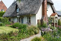 Caynton Cottage, une chaumière du XVIIe siècle, surplombe une pelouse et des sentiers bordés de vivaces.