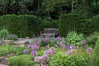 Le jardin de Sylvia à Newby Hall, un banc installé dans une haie d'ifs surplombe la disposition formelle et enfoncée des parterres de fleurs.