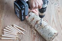 Gros plan sur l'utilisation d'une perceuse sans fil pour faire des trous de bougie en bois de bouleau