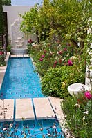 Un jardin exotique avec un large ruisseau d'eau et des parterres luxuriants de grenadiers et de roses